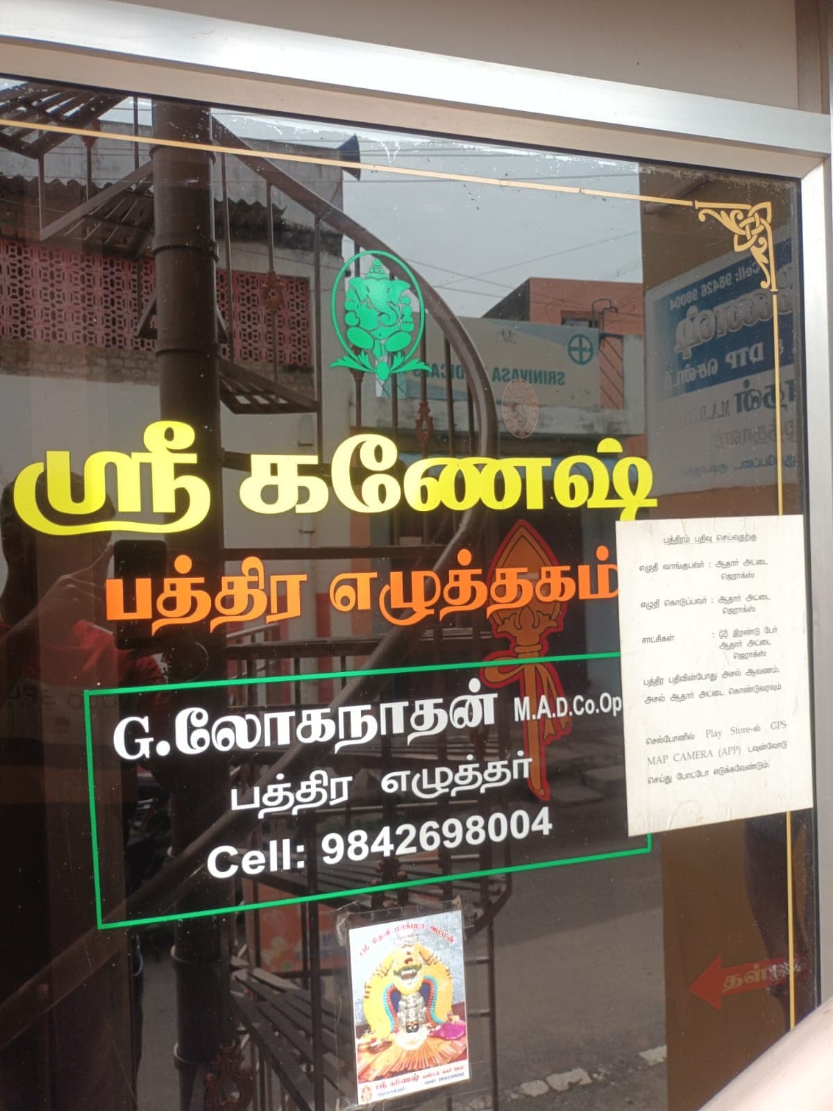 கண்ணாடிக் கதவில் ஸ்ரீ கணேஷ் பத்திர எழுத்தகம், G. லோகநாதன் M.A., D.Co-op., பத்திர எழுத்தர், Cell 9842698004 என எழுதப்பட்டுள்ளது.